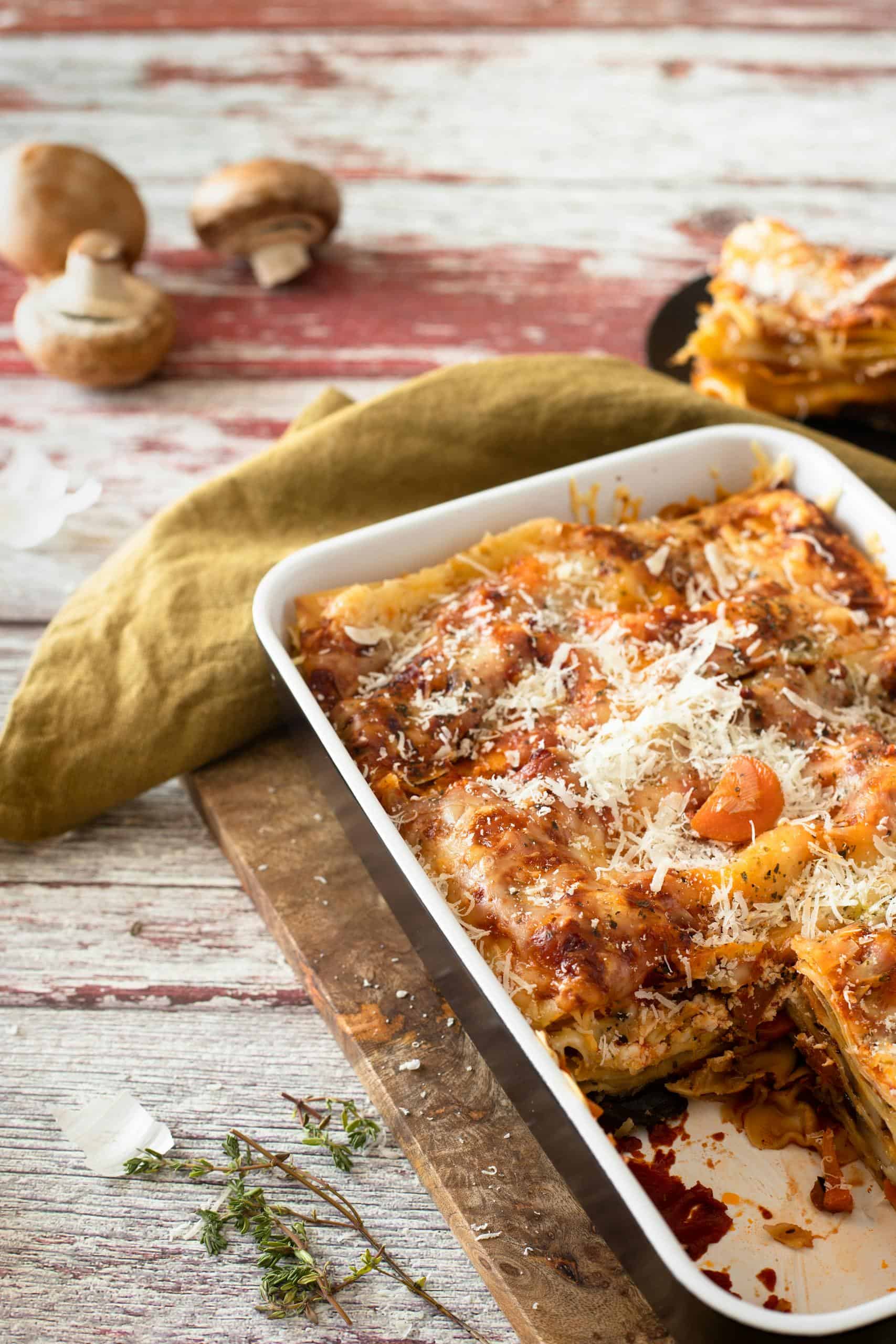 Close-up of traditional Italian lasagna with grated cheese and rustic styling.