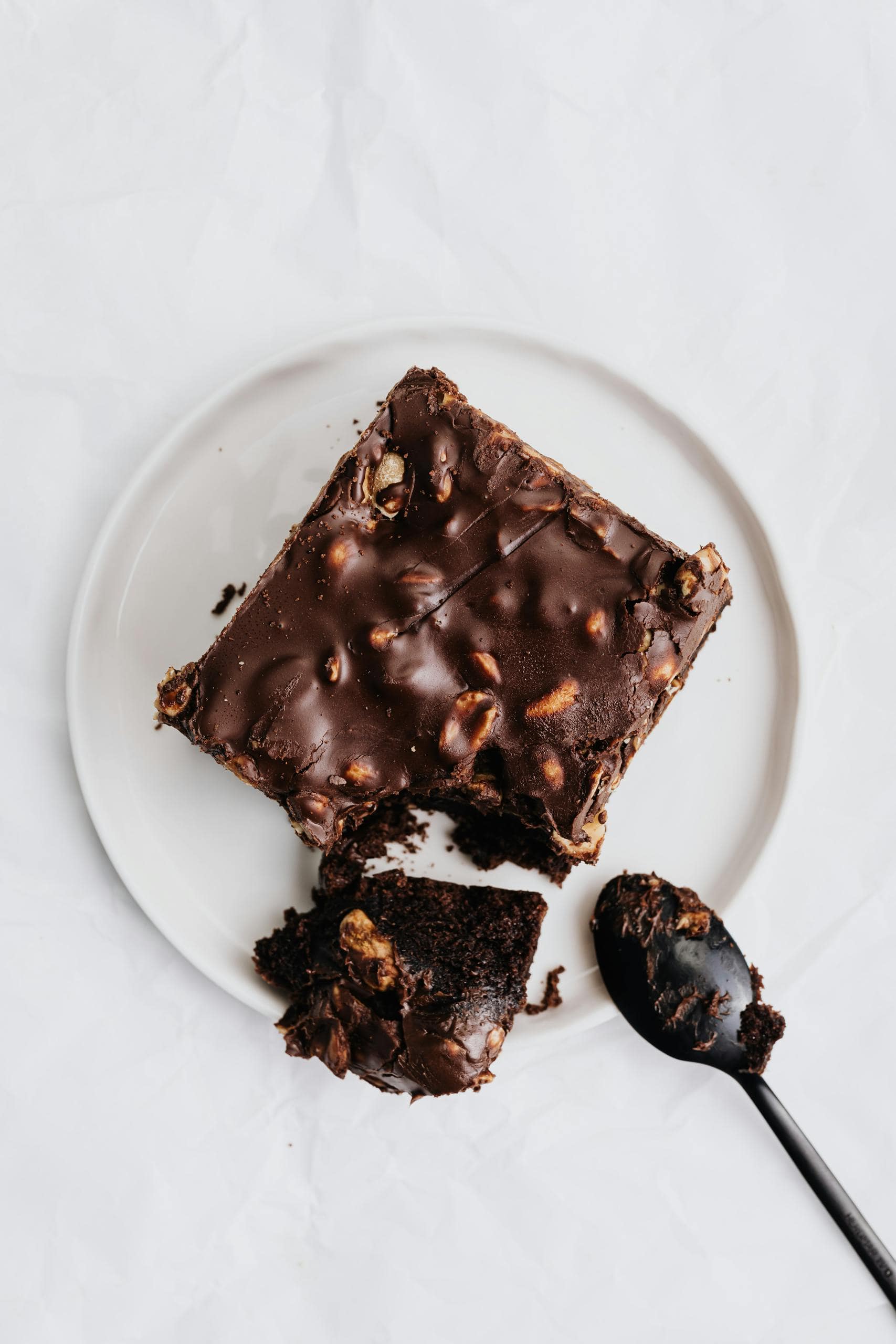 Indulgent chocolate brownie with nuts on a plate and spoon. Perfect dessert.