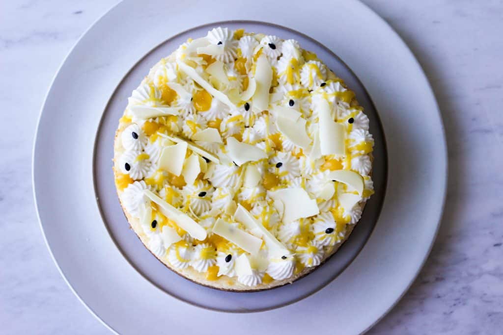 White chocolate cheesecake with passion fruit curd in a white serving plate.