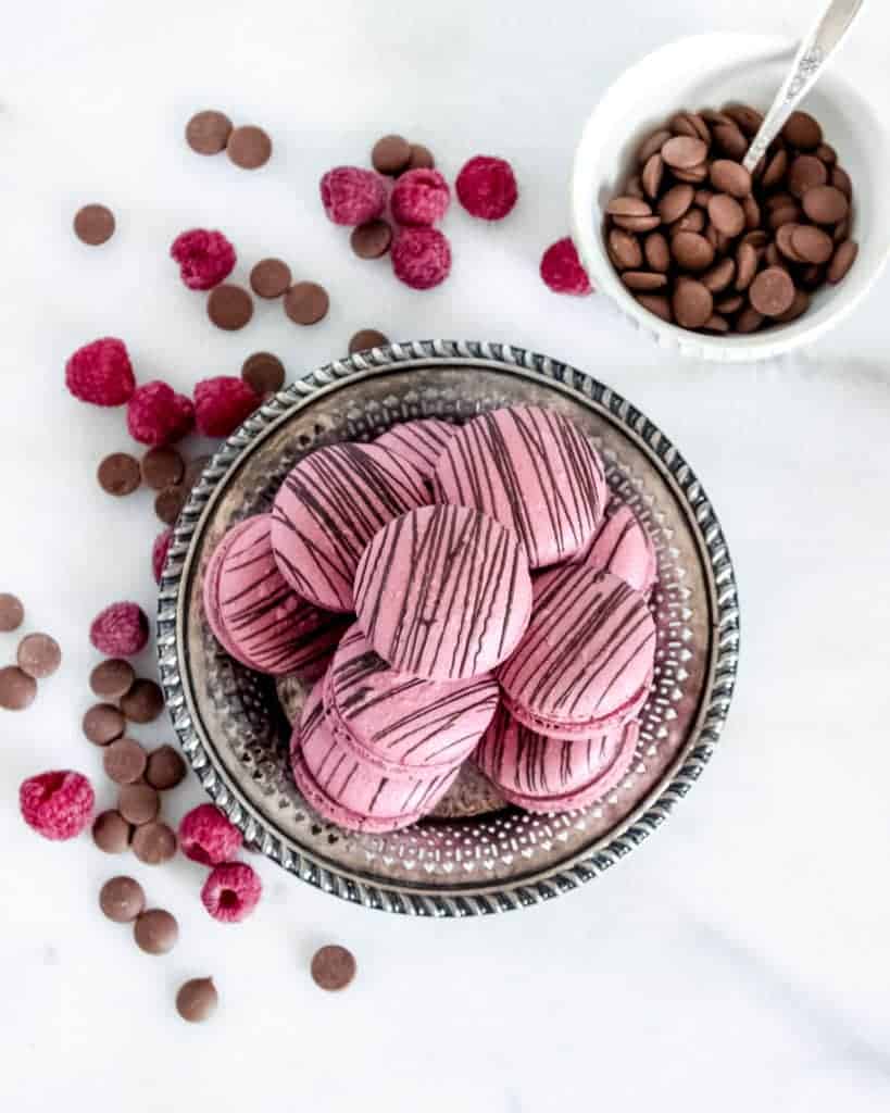 Raspberry macarons with dark chocolate chips and fresh raspberries.