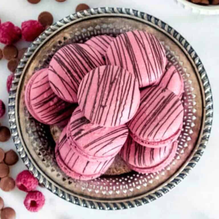 Raspberry macarons with dark chocolate in a vintage round plate