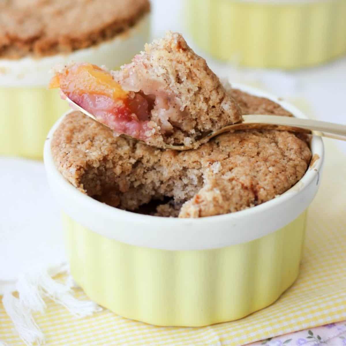 Baked peach and plum cobbler with golden topping in a ramekin.