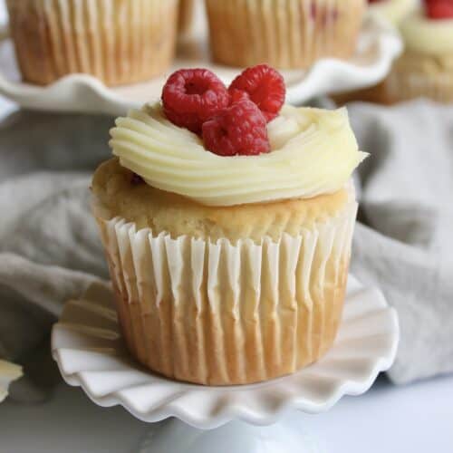 Raspberry cupcakes with white chocolate ganache and garnished with fresh raspberries.