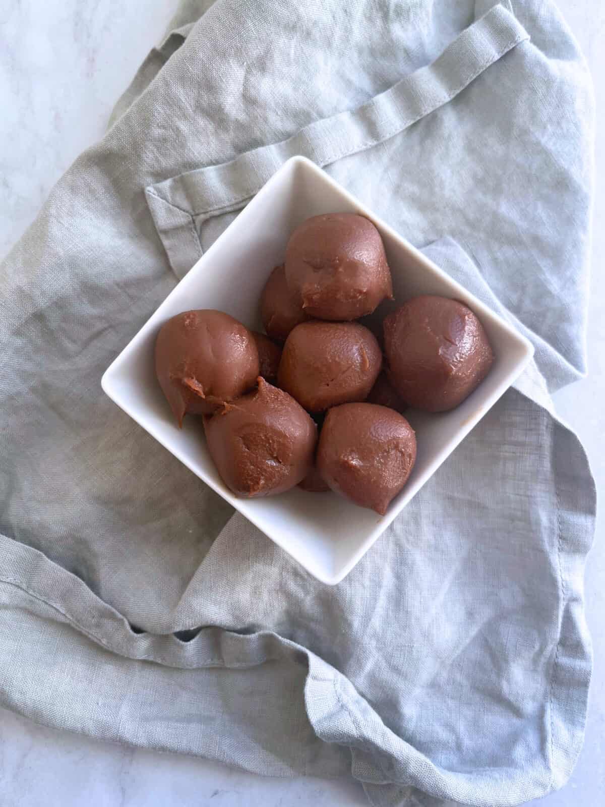 Creamy fudge filling portioned in small bowls in a square bowl ready to stuff cookies.
