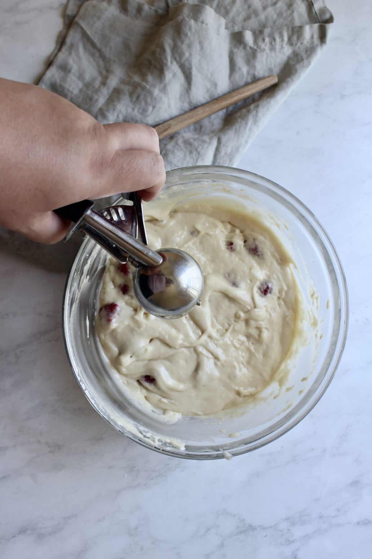 Scooping white chocolate and raspberry cupcake batter