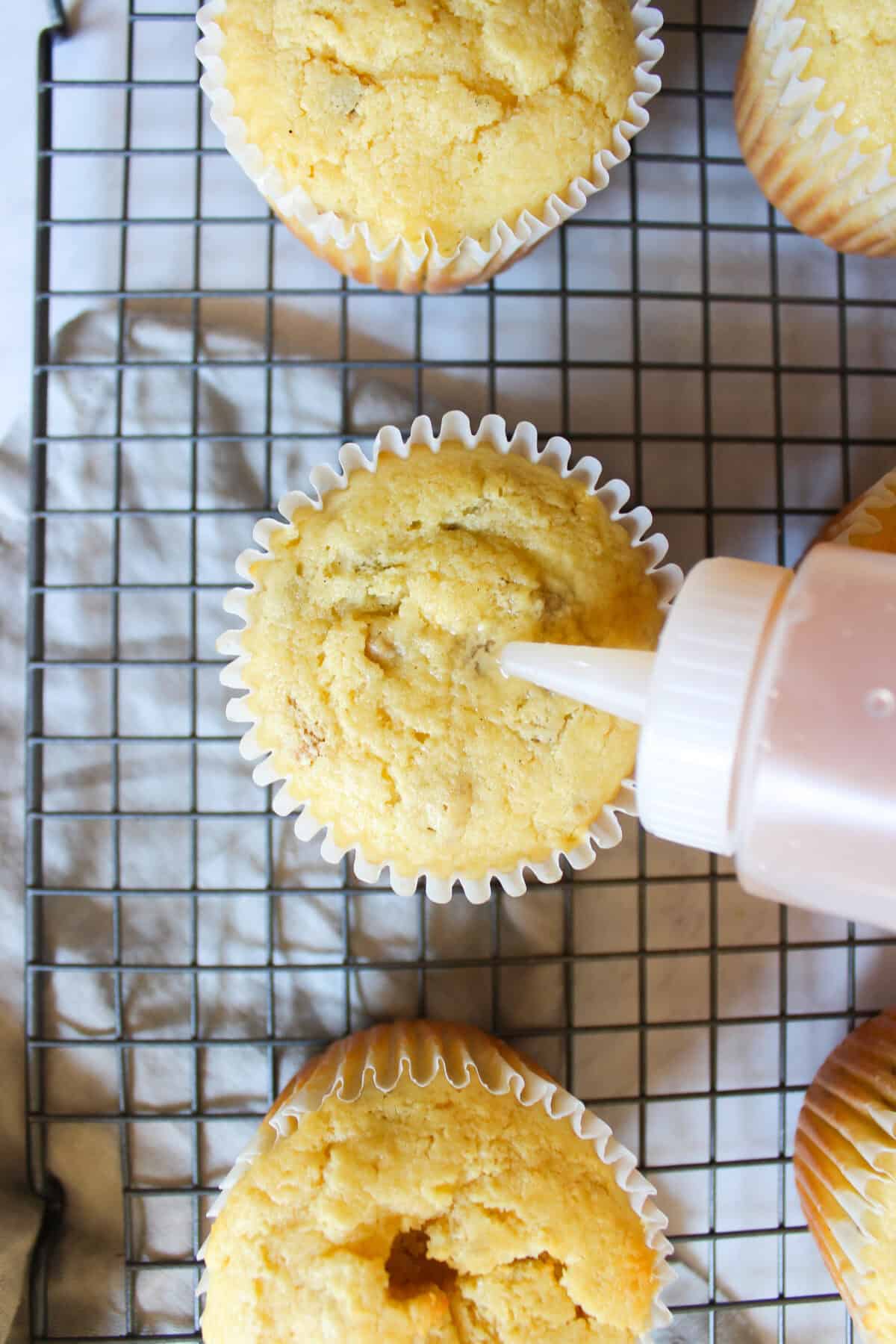 Pear syrup being drizzled over warm cupcakes