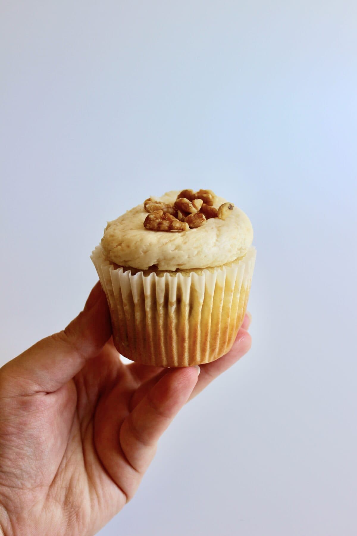 Frosted pear cupcakes decorated with chopped walnuts on a white background.